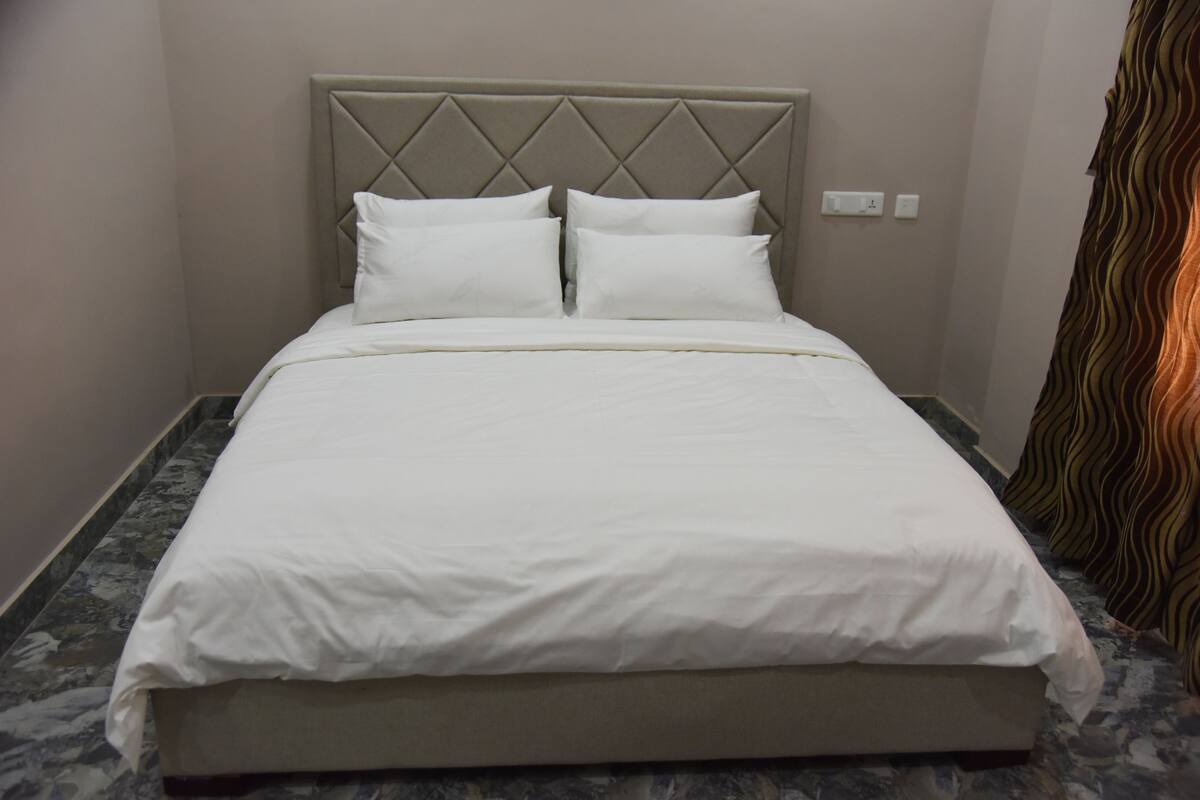 Ein Bett mit Kopfteil, zwei Kissen und einer weißen Bettdecke.
