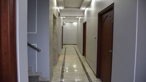 A corridor with a marble floor, wooden doors, and a handrail.