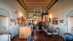 A spacious room with a large wooden dining table, a chandelier, and a staircase leading to an upper level.