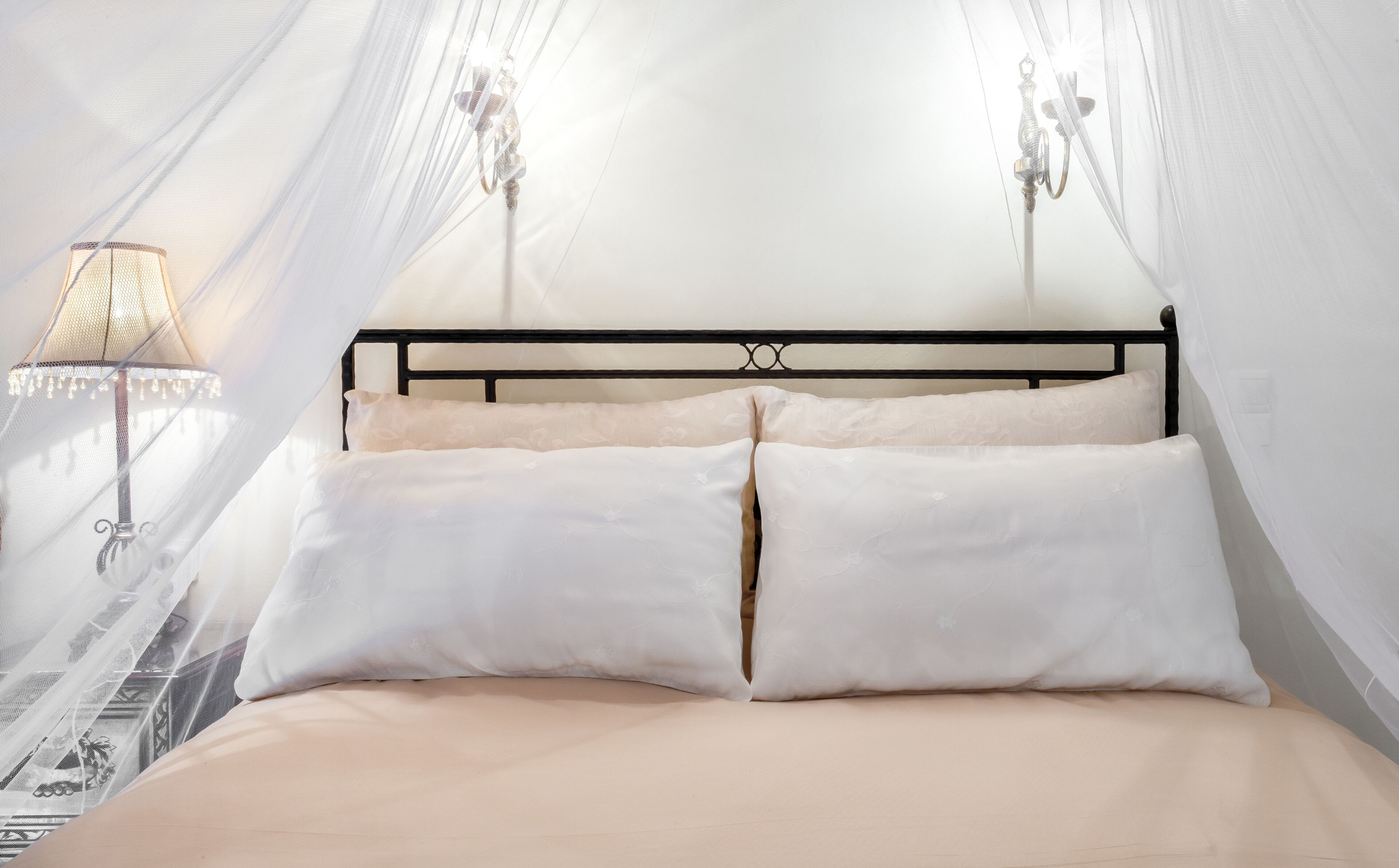 Una cama con dosel, dos lámparas de noche y un papel tapiz estampado.