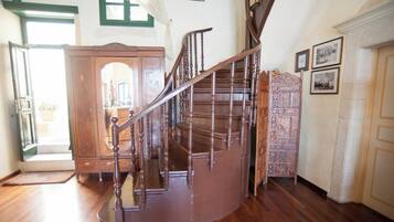 A wooden staircase with a handrail, a wooden door, and a wall with framed pictures.