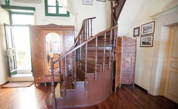 A wooden staircase with a handrail, a wooden door, and a wall with framed pictures. - Casa Leone Hotel (Chania)