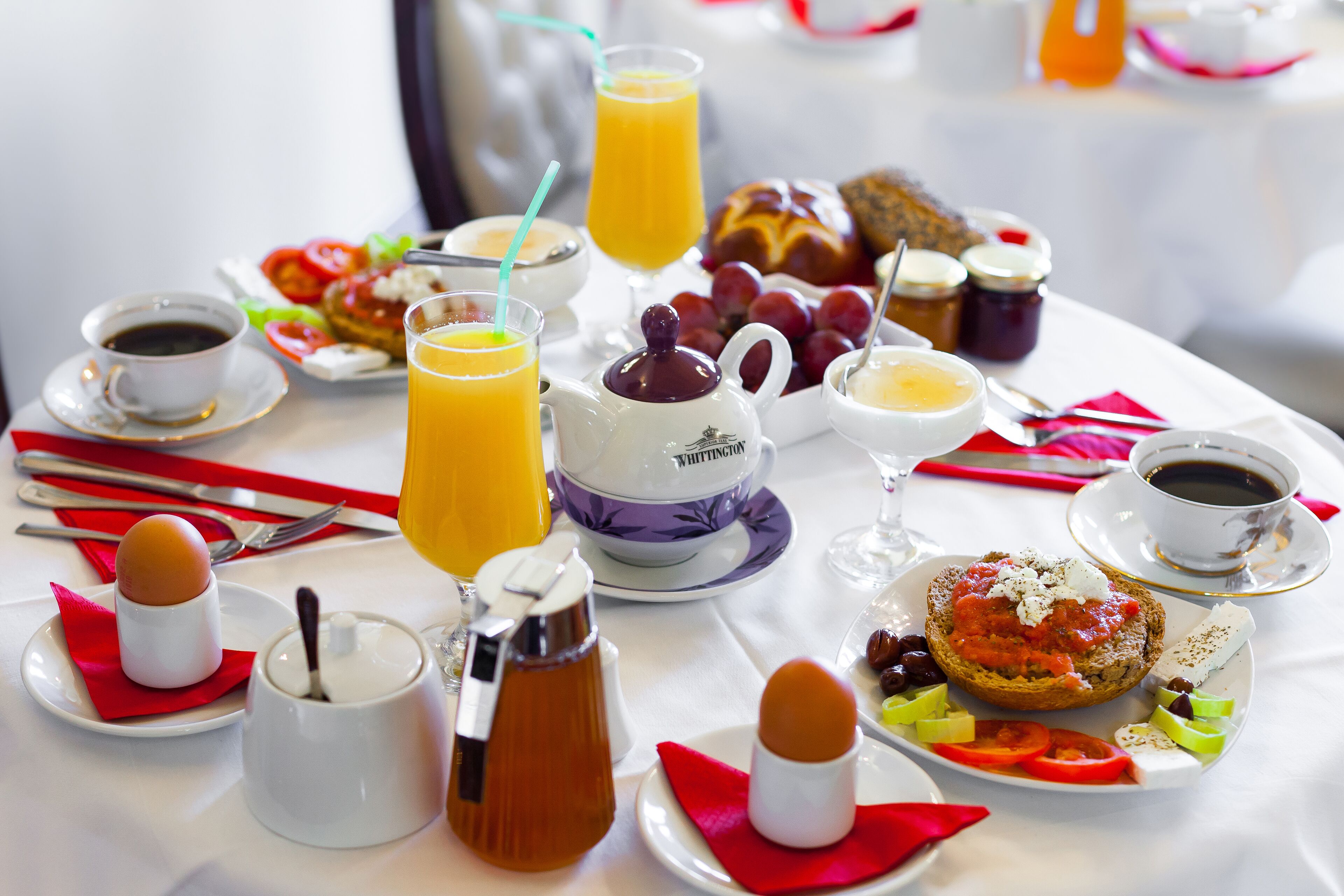 A breakfast table with various food items and drinks, including toast, eggs, and orange juice.