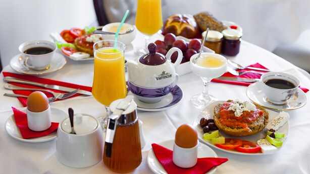 Una mesa de desayuno con diversos alimentos y bebidas, como tostadas, huevos y jugo de naranja.