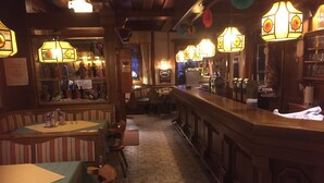Zona de bar con suelo de baldosas hexagonales, barra de madera y farolillos de papel colgantes.