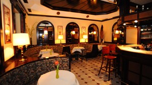 Un restaurante con barra, mesas redondas y cabinas.
