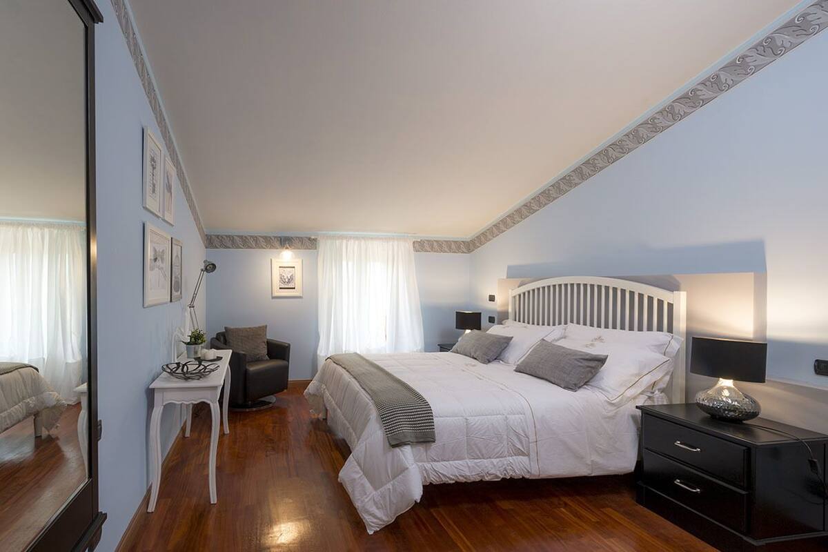A bedroom with a large bed, bedside tables, a desk, and a chair.