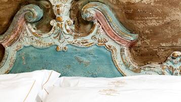 A bed with a white sheet and a decorative headboard with intricate carvings.
