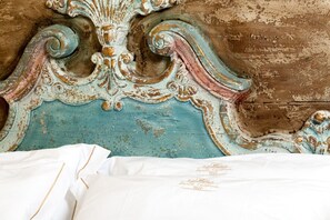 A bed with a white sheet and a decorative headboard with intricate carvings. - Relais Santa Caterina (Viterbo)