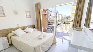 A hotel room with a bed, a desk, and a balcony with a view of the city. - HSR Gil  (Calvia)