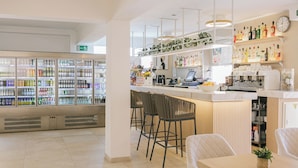 A modern bar area with a counter, stools, and a variety of beverages. There is a refrigerator filled with drinks and a clock on the wall. - HSR Gil  (Calvia)
