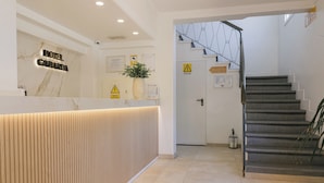A hotel reception desk with a marble wall, a wooden reception counter, and a staircase leading to the upper floor. - HSR Gil  (Calvia)