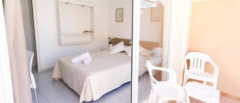 A bedroom with a bed, a chair, and a small table.