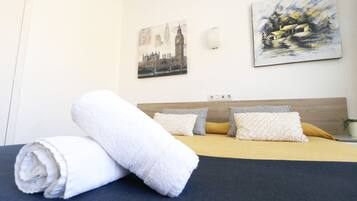 A neatly made bed with a rolled white towel, a wooden headboard, and two pillows.