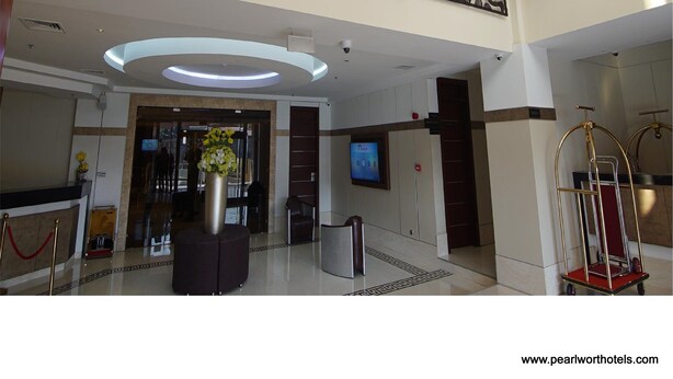 A modern hotel lobby with a reception desk, a large digital screen, and artwork on the walls. - Pearlwort Hotel and Suites (Lagos)