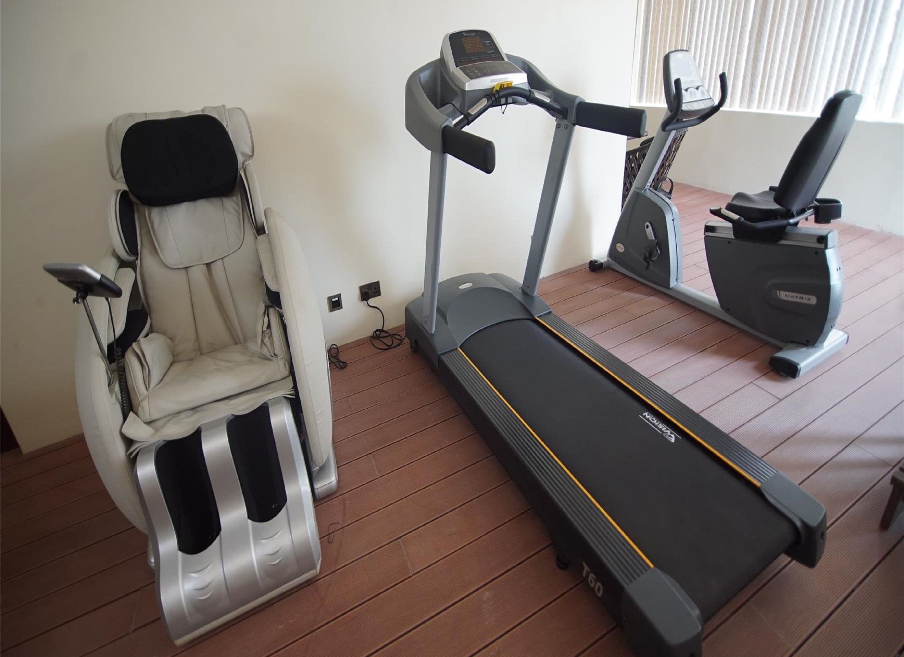 A home gym with a massage chair, a treadmill, and an elliptical machine.