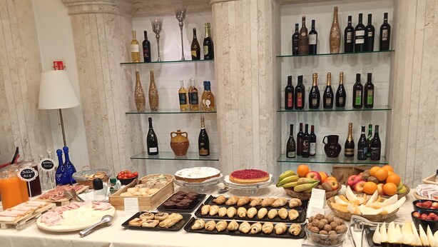 A buffet table with various food items and a wine selection. - BHB Hotel (Manduria)