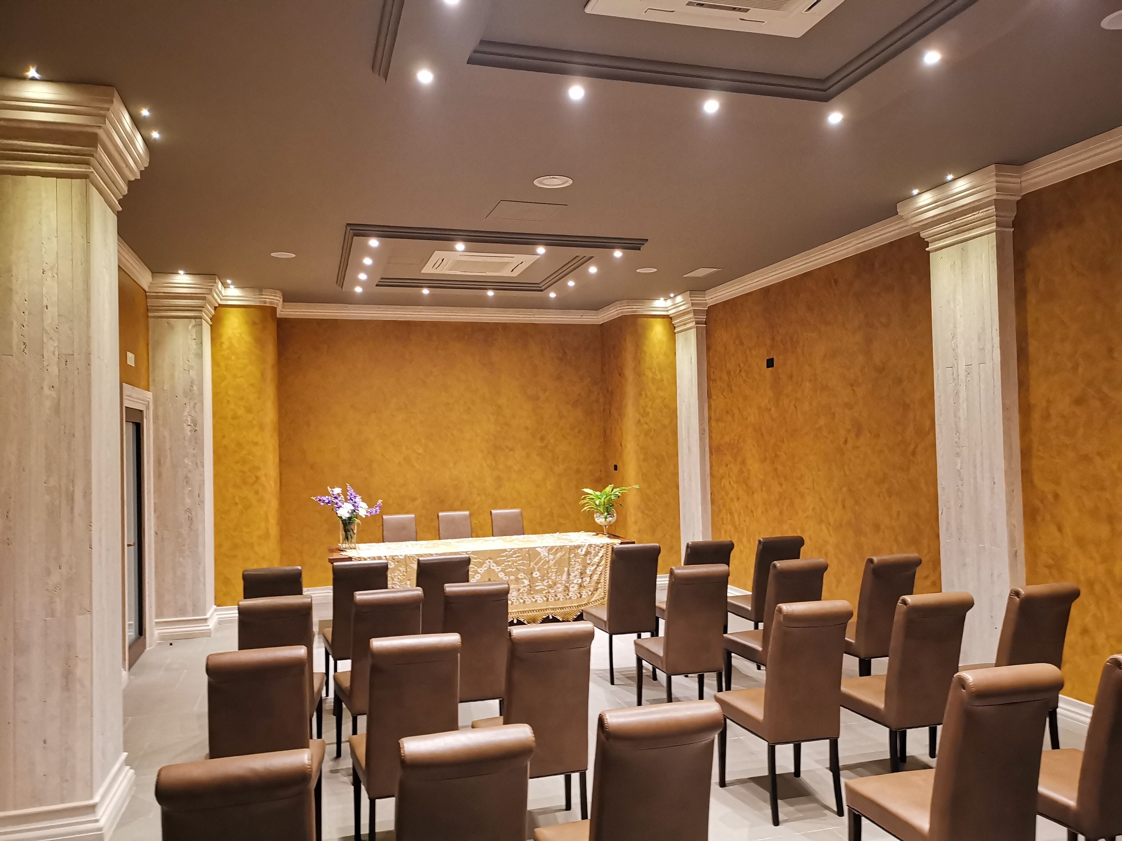 A conference room with a long table, multiple chairs, and a decorative vase.