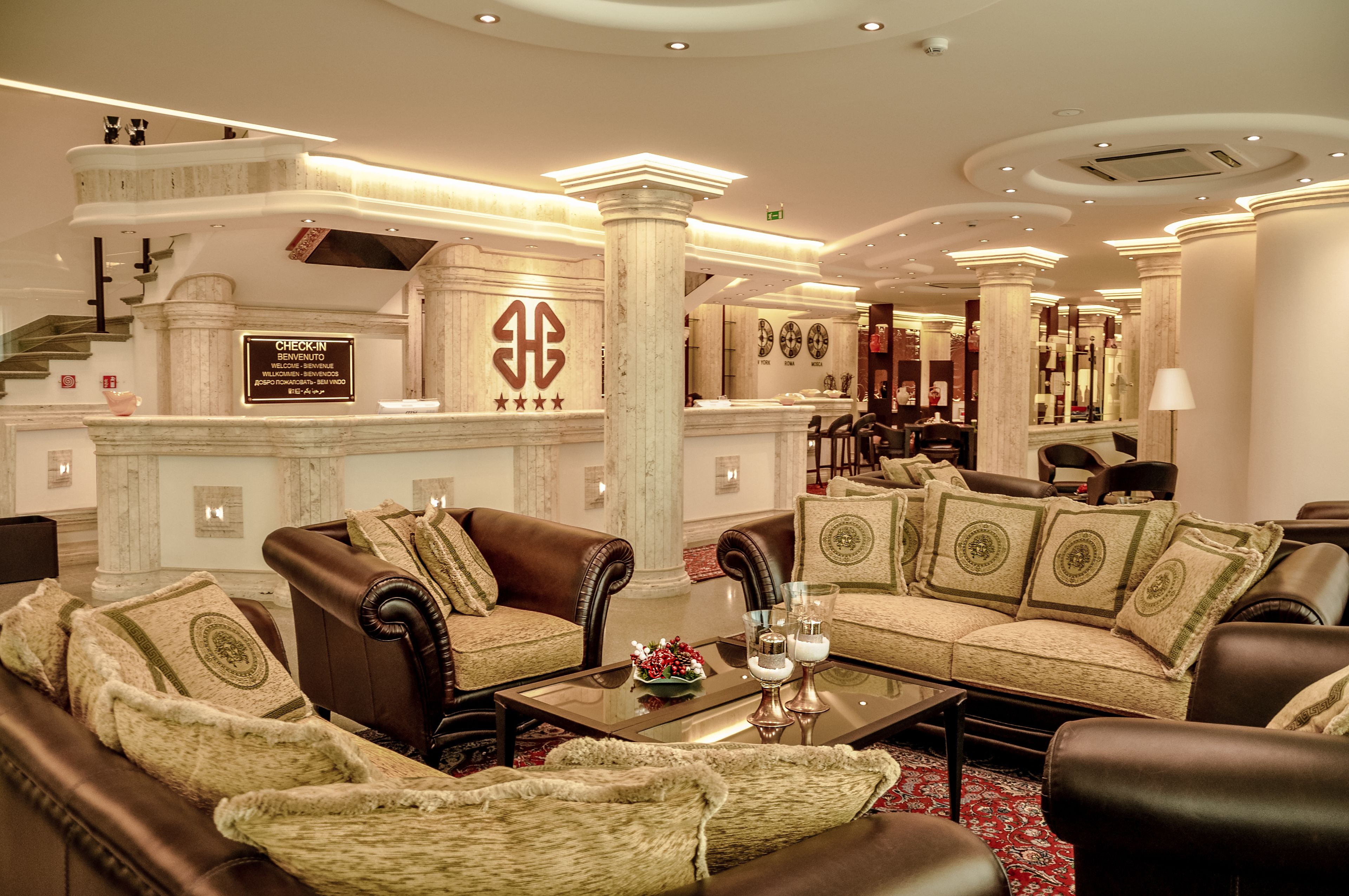 A luxurious lobby with marble columns, leather sofas, and a check-in desk.
