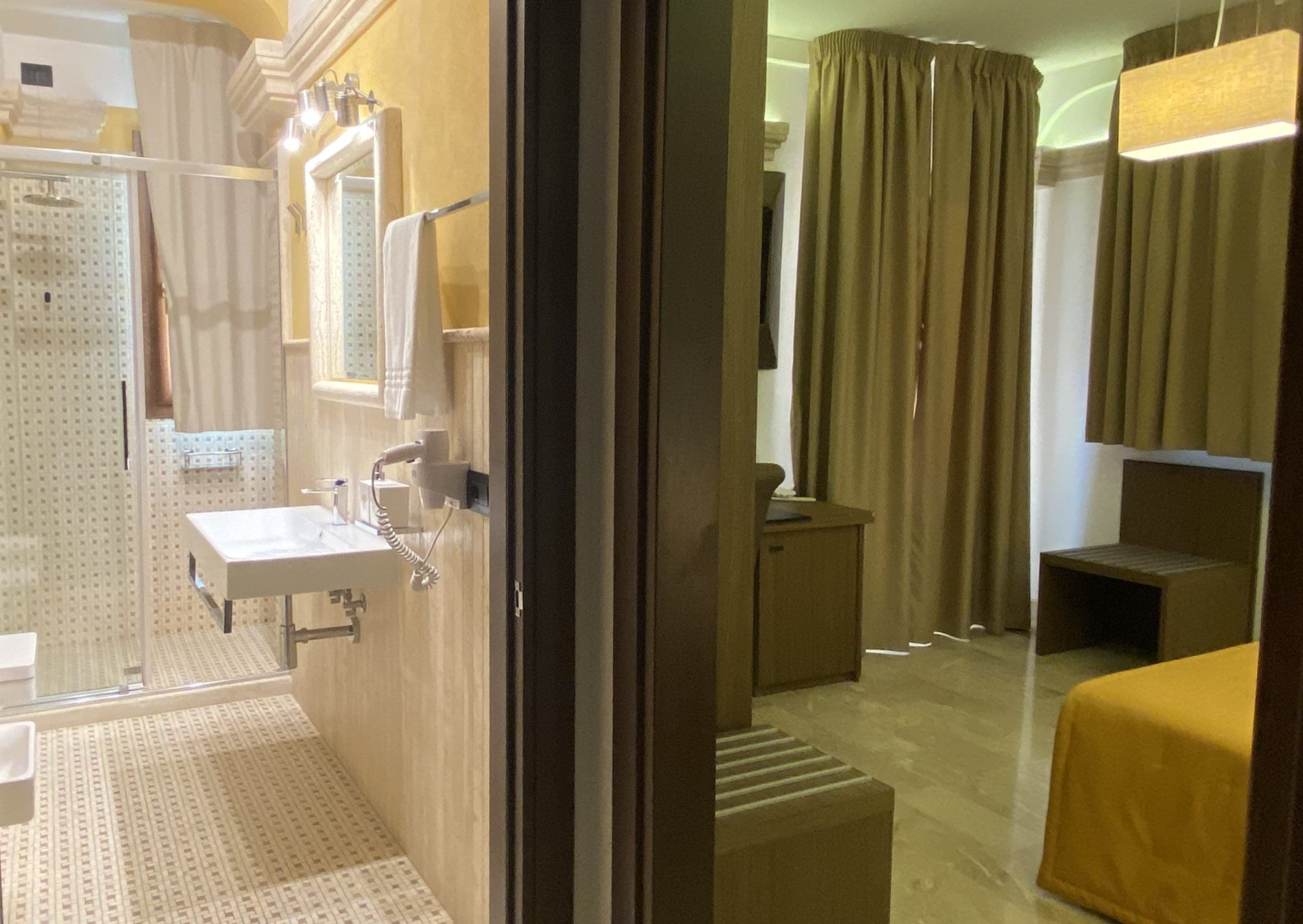 Un baño de hotel con lavamanos, espejo y zona de ducha.