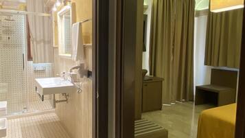 Un baño de hotel con lavamanos, espejo y zona de ducha.