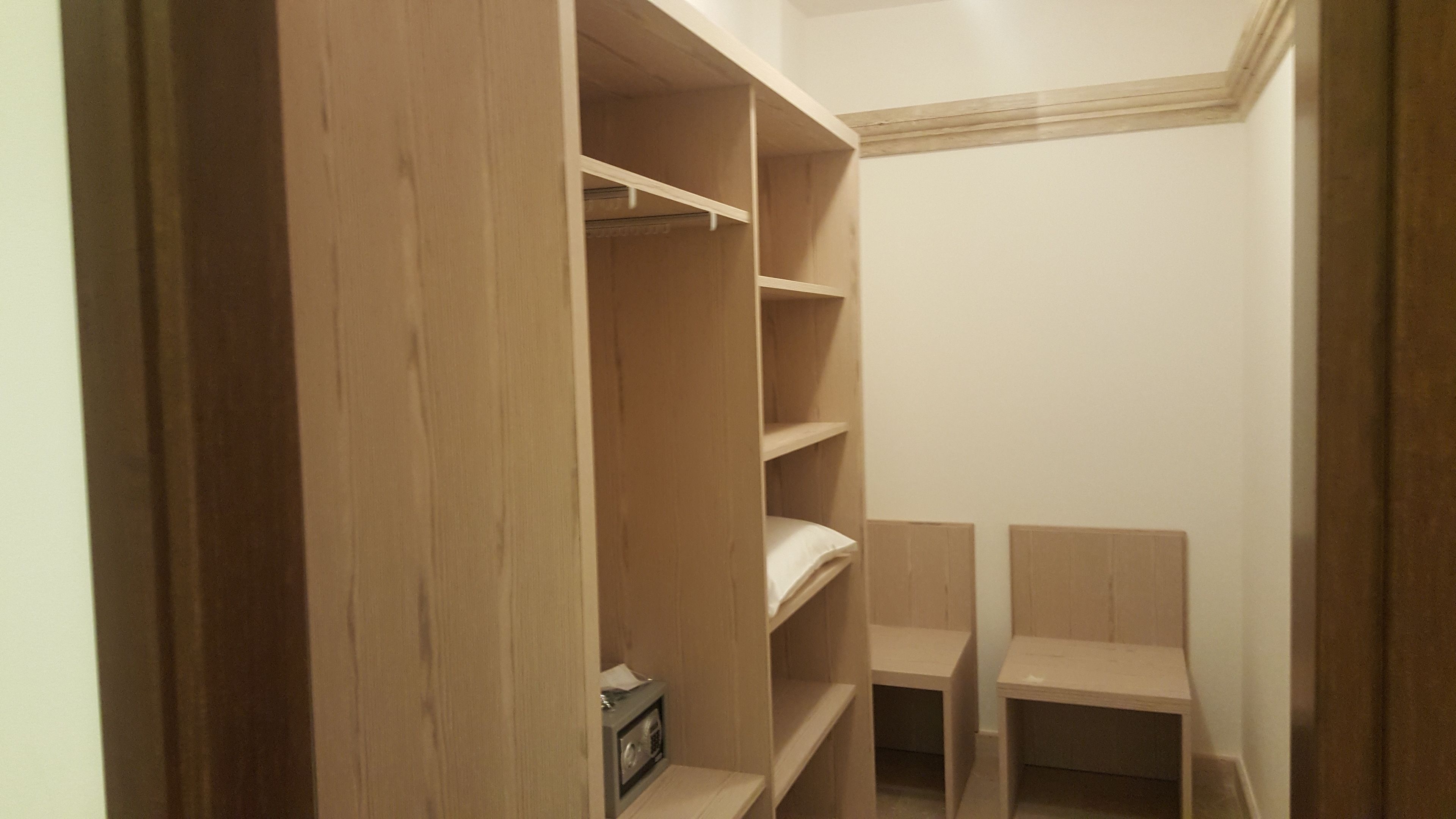 A walk-in closet with wooden shelving and a small radio on the bottom shelf.