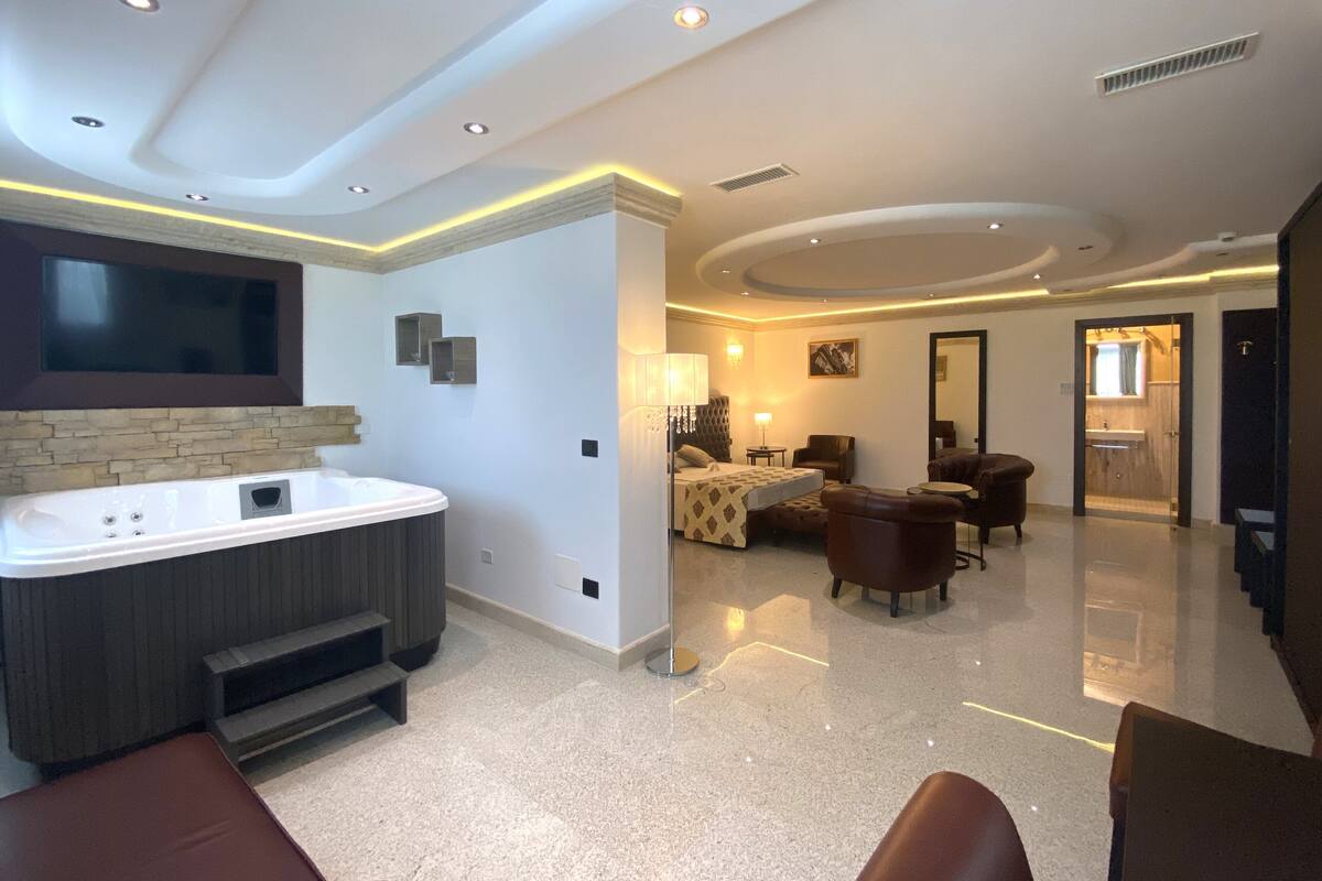 Amplia sala de estar con un televisor de pantalla plana grande, un jacuzzi y una zona de estar con sillones de cuero.