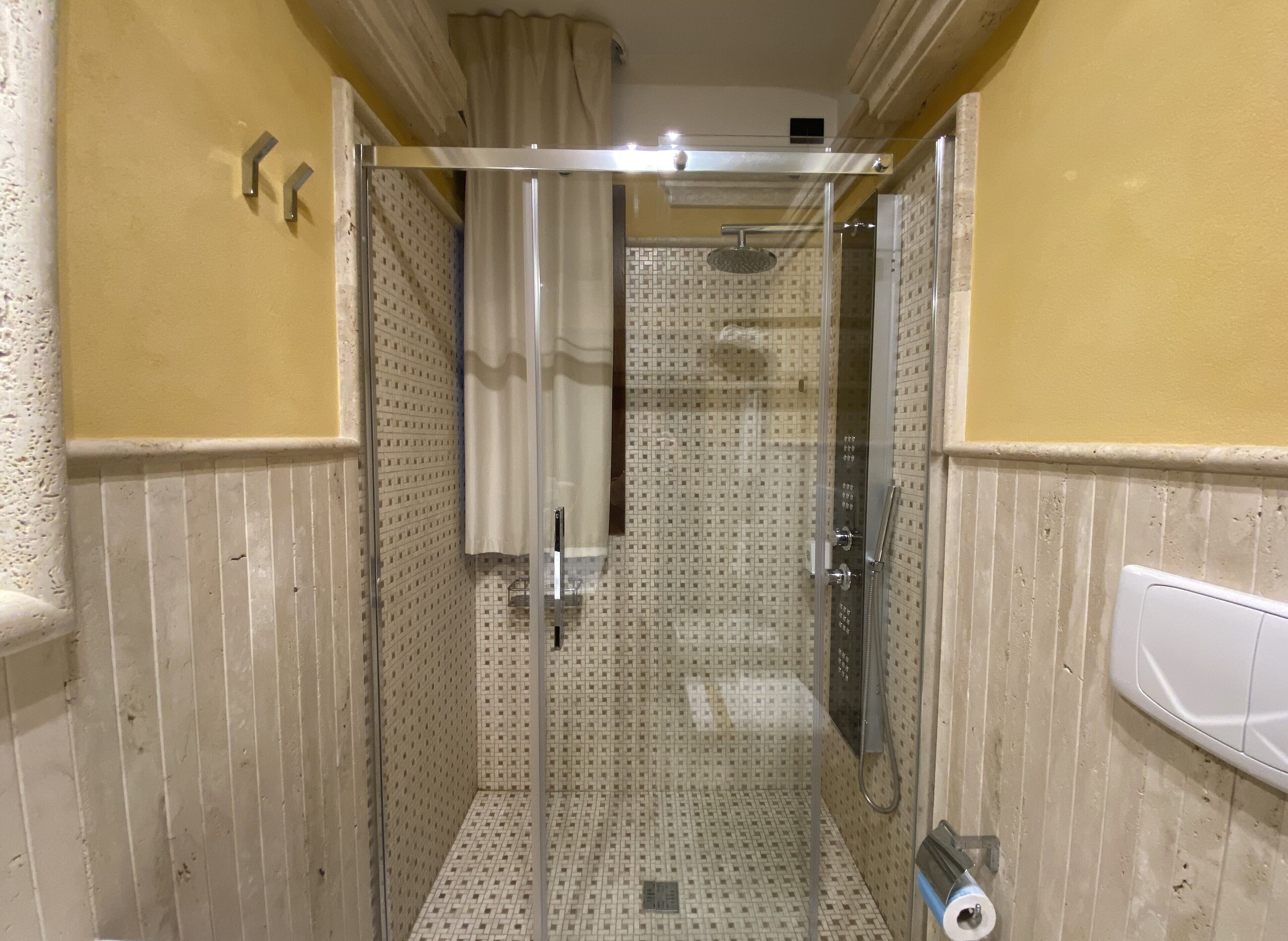 Un baño estrecho con zona de ducha, paredes con azulejos y un inodoro.