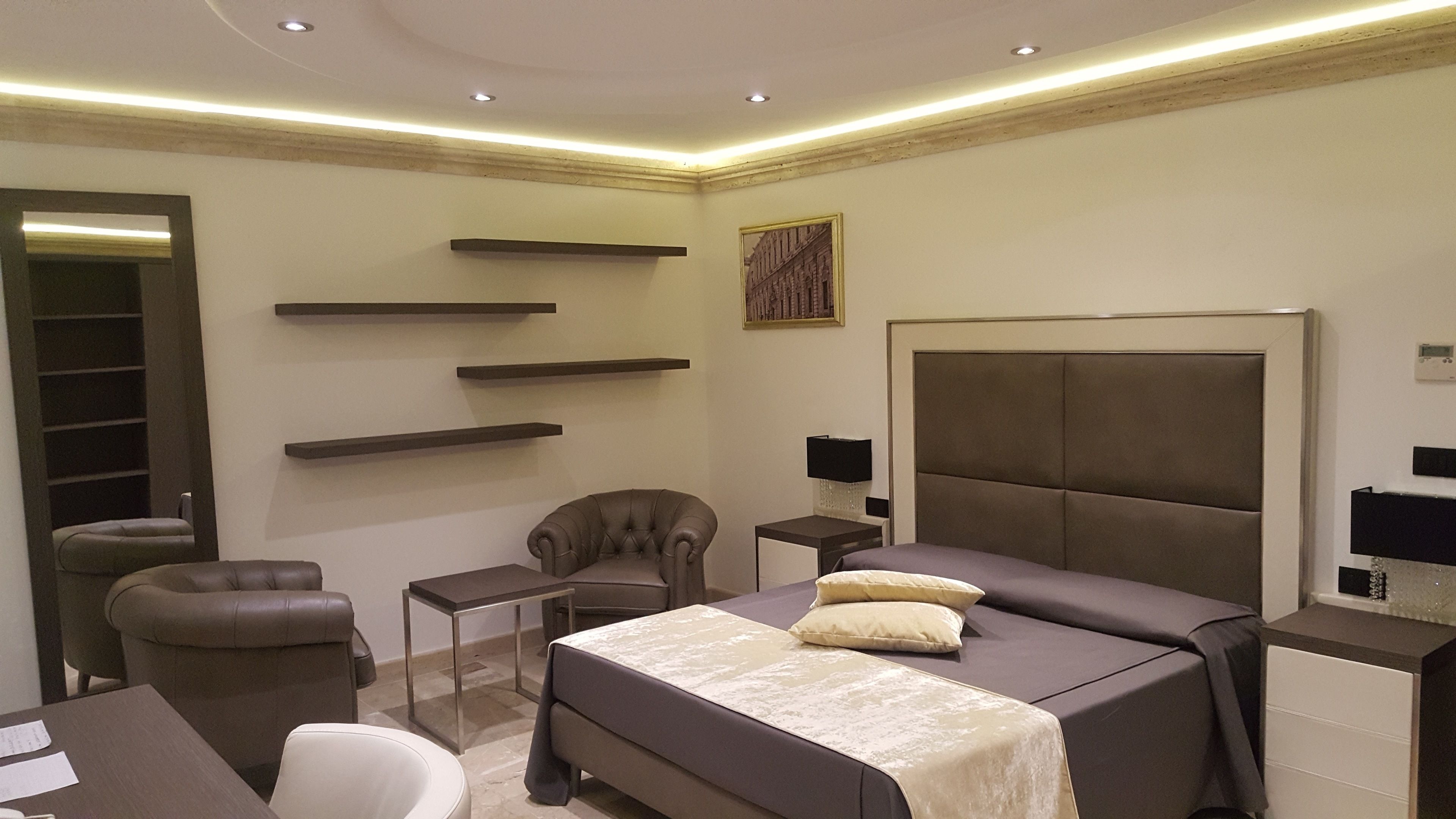 Quarto moderno com uma cama grande, uma cadeira, uma escrivaninha e prateleiras embutidas.