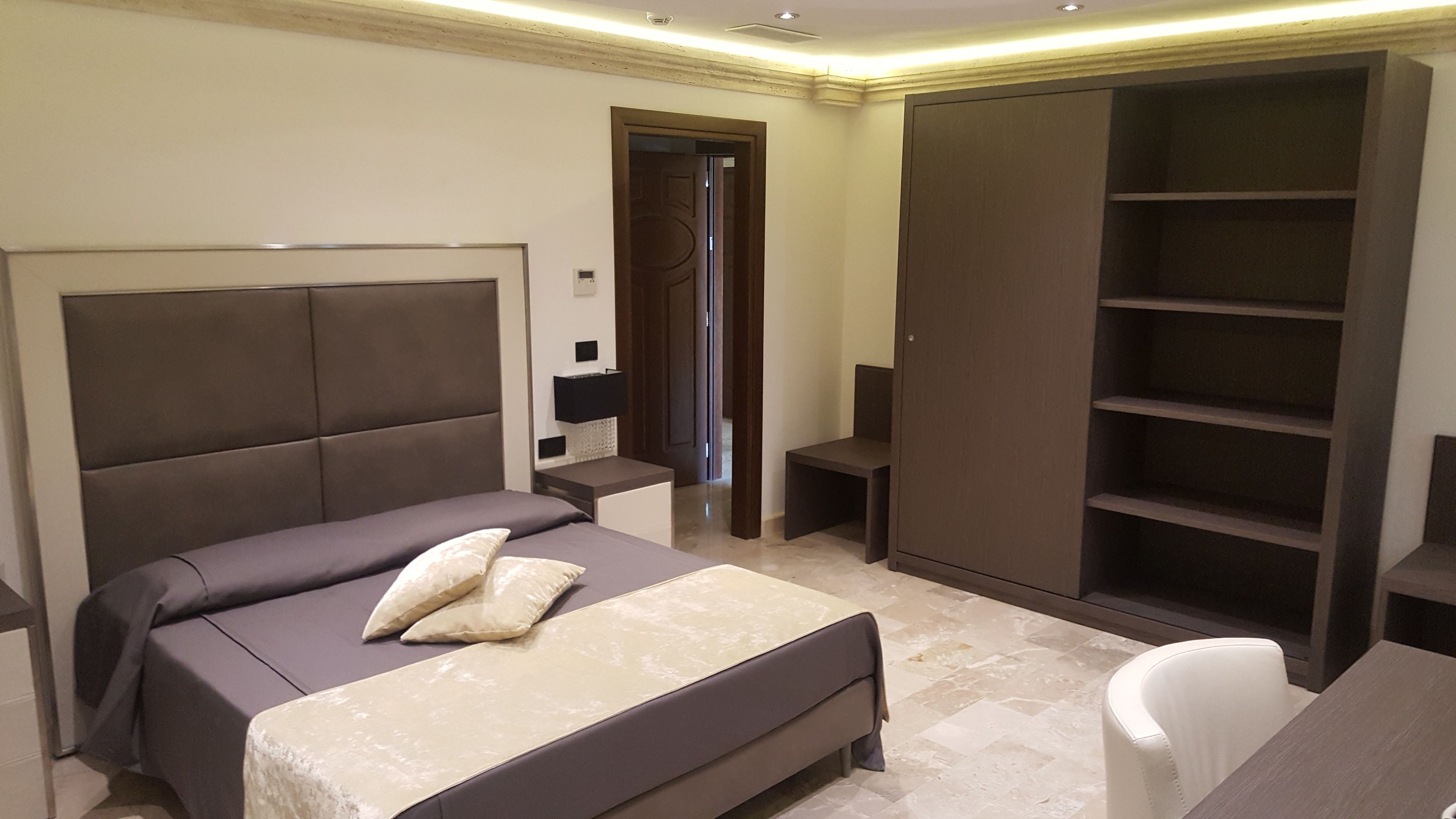 Un dormitorio con una cama grande, un armario, un escritorio y una silla.