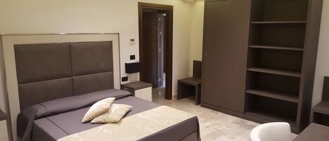 Un dormitorio con una cama grande, un armario, un escritorio y una silla.