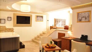 A modern hotel room with a hot tub, a dining area with a fruit bowl, a wooden desk, and a staircase. - BHB Hotel (Manduria)
