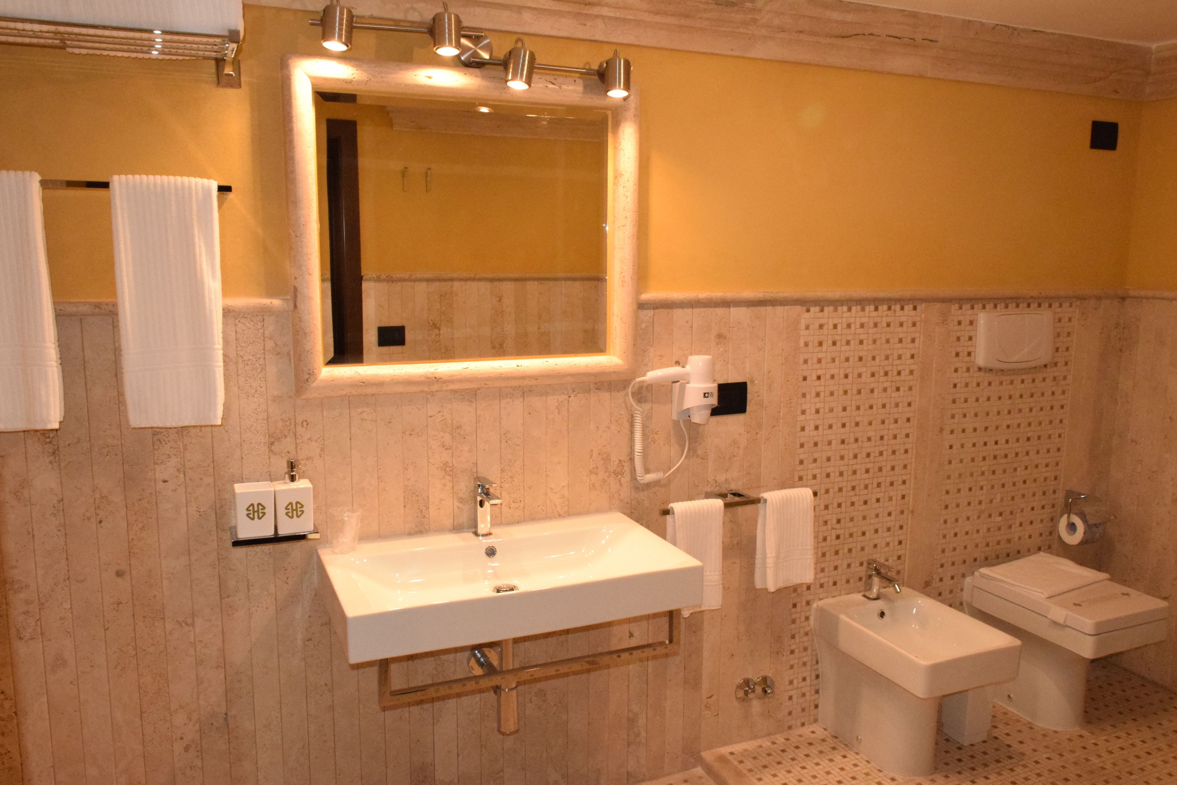Un bagno con un grande specchio, un lavandino, un water e uno spazio doccia.