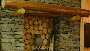A stone fireplace with a fire, logs stacked above, and a guitar leaning against the wall. - Inan Kardesler Hotel (Çaykara)