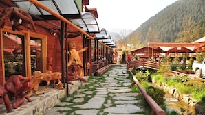 A rustic wooden building with a stone pathway leading to a covered seating area. - Inan Kardesler Hotel (Çaykara)