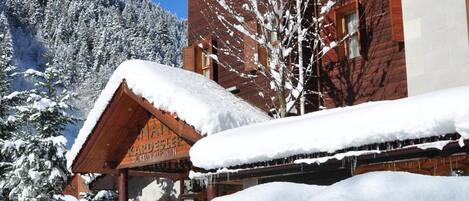 Un edificio de madera con techo nevado y un letrero que dice "Hotel KARDESER".