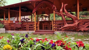 A wooden building with a covered porch, stone steps, and a large tree trunk integrated into the structure. - Inan Kardesler Hotel (Çaykara)
