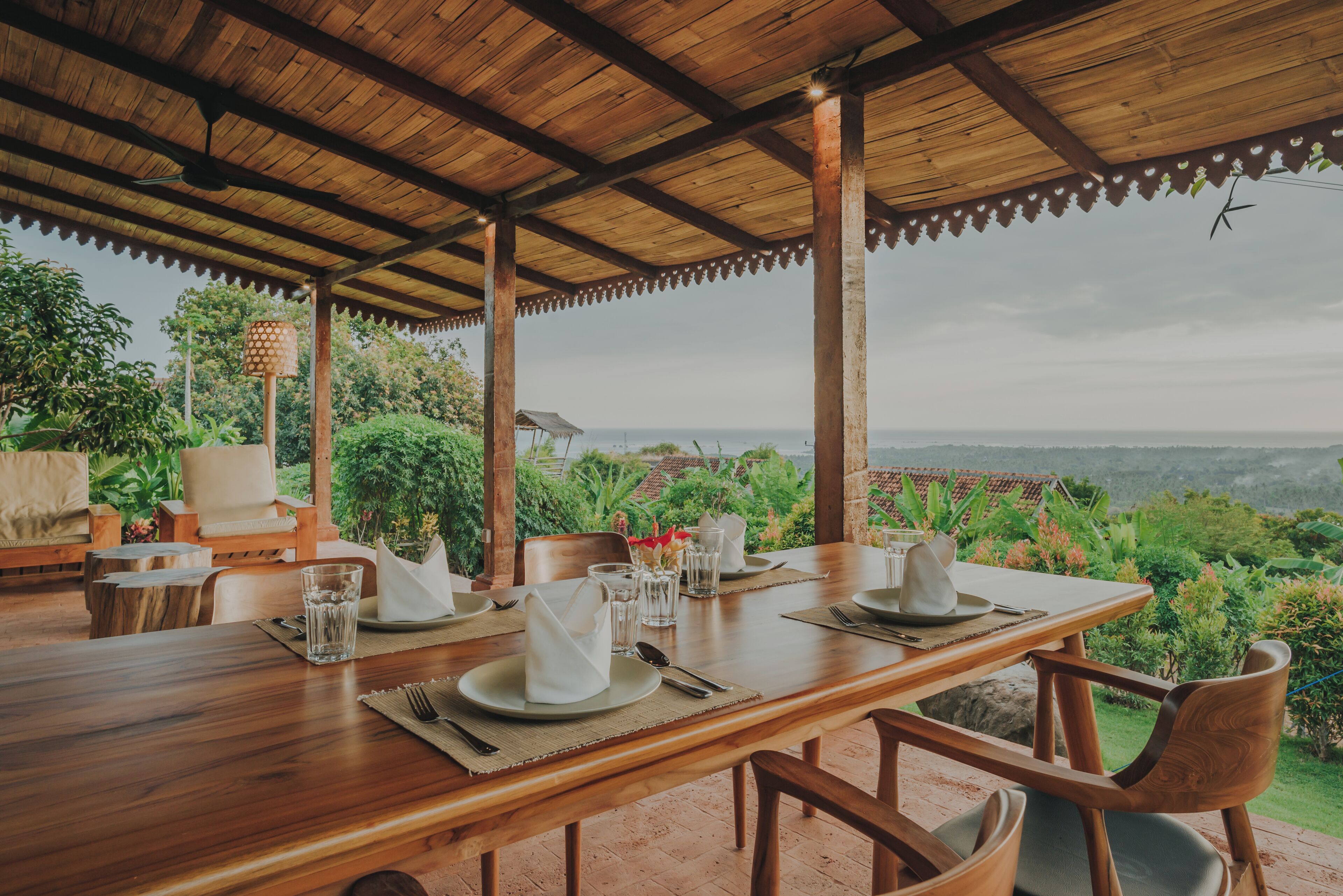 A wooden dining table set for four with a view of the landscape.