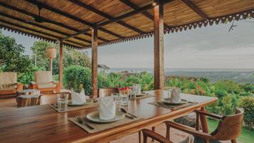A wooden dining table set for four with a view of the landscape.
