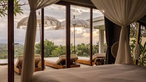 A bedroom with a large window, a bed, and two lounge chairs. - Sumberkima Hill Private Villa Retreat (Pemuteran)