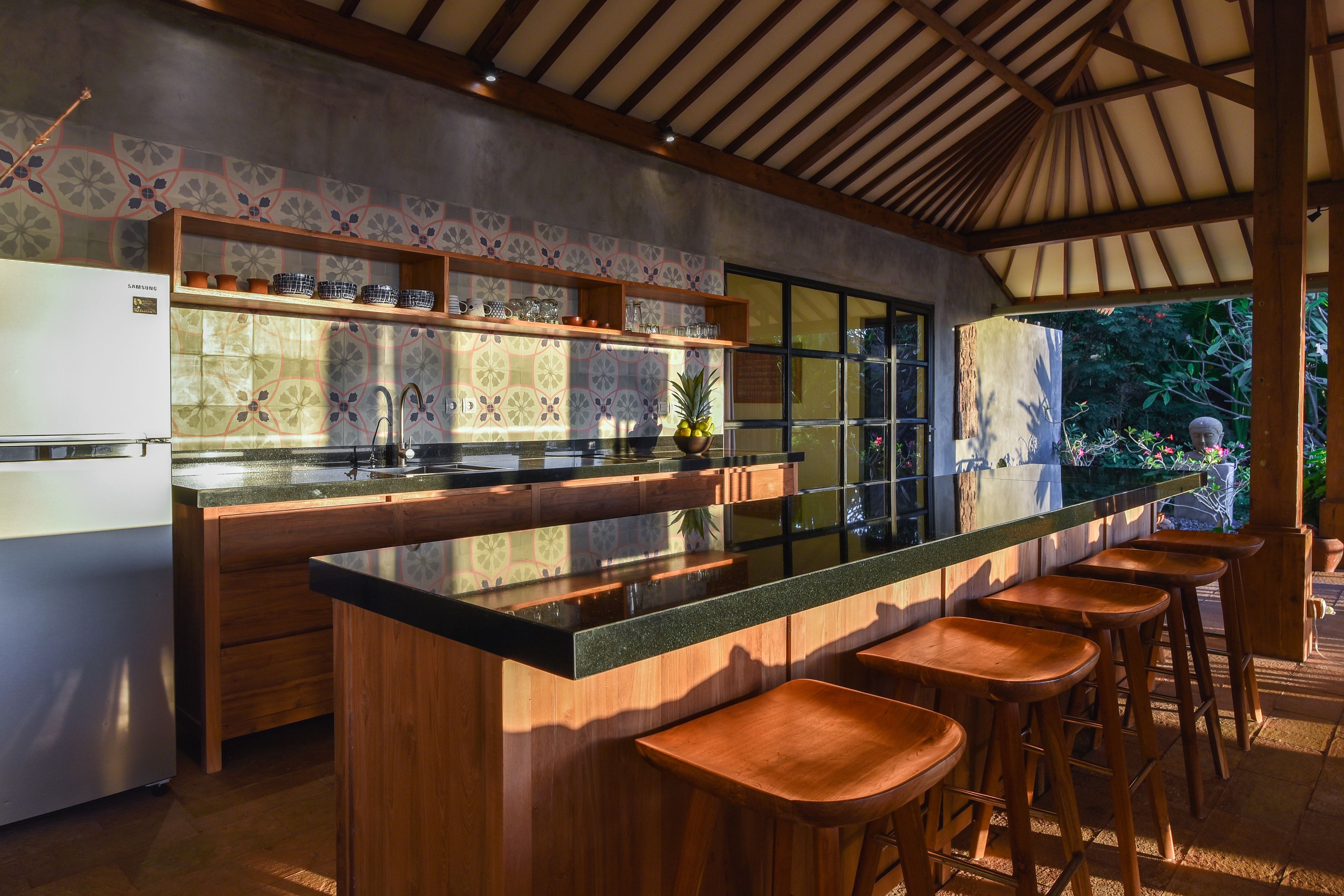 A modern kitchen with a central island, bar stools, and a refrigerator.