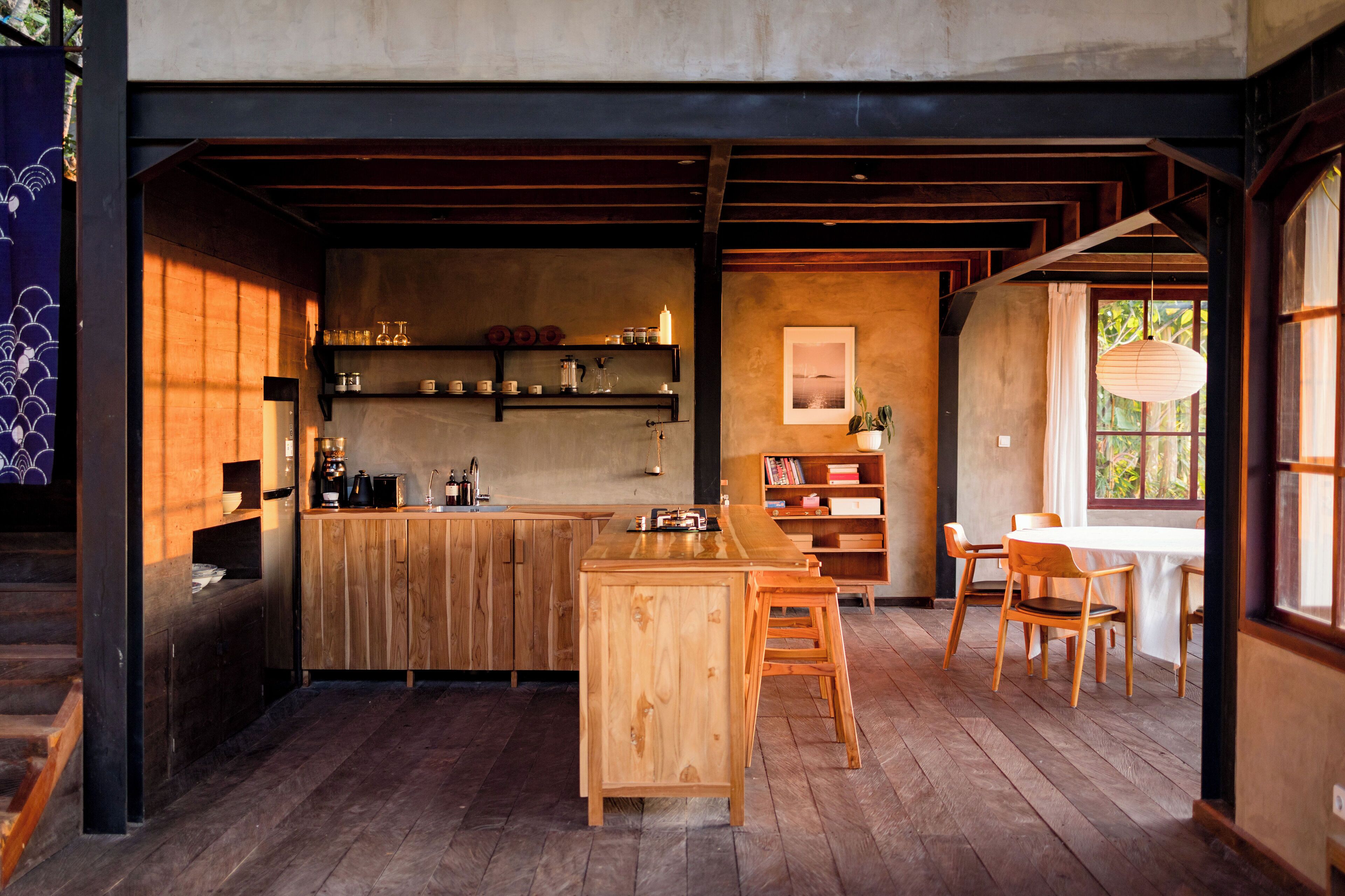 Una cocina moderna con armarios de madera, una isla central y un comedor con sillas y una mesa de madera.