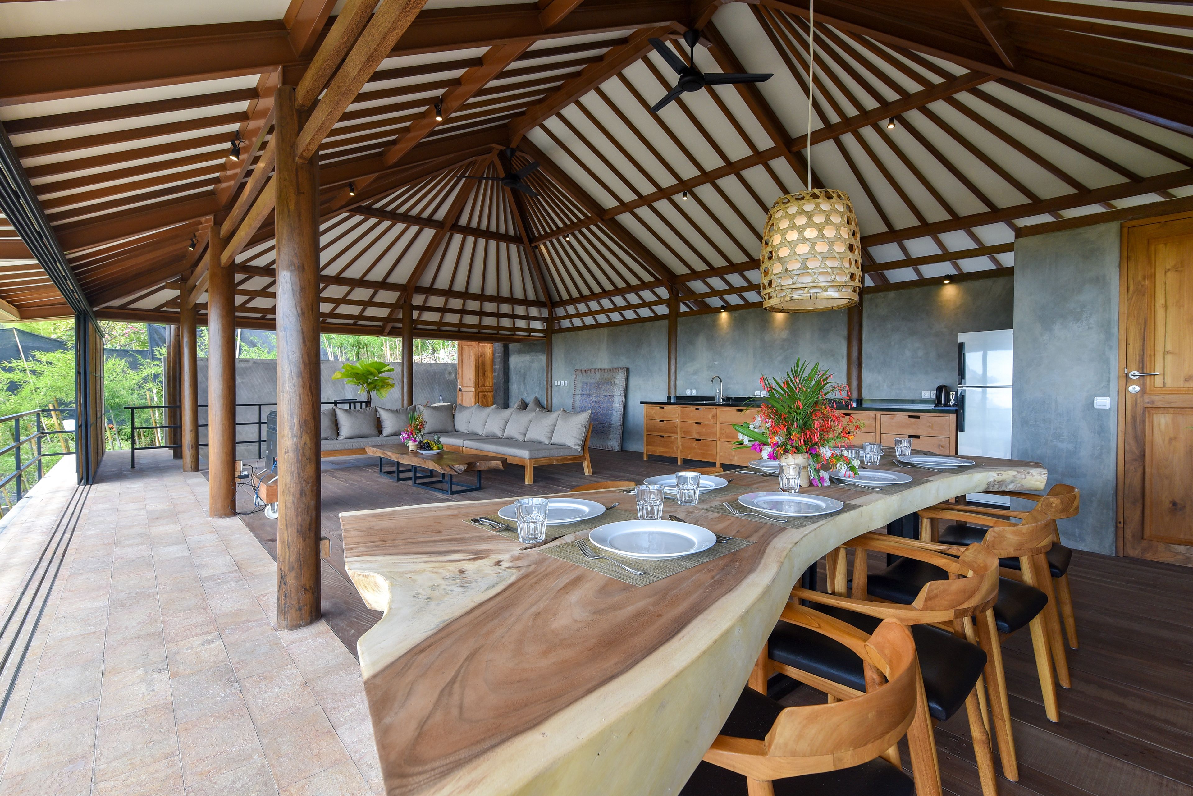 A spacious dining area with a long wooden table, multiple chairs, and a hanging light fixture.