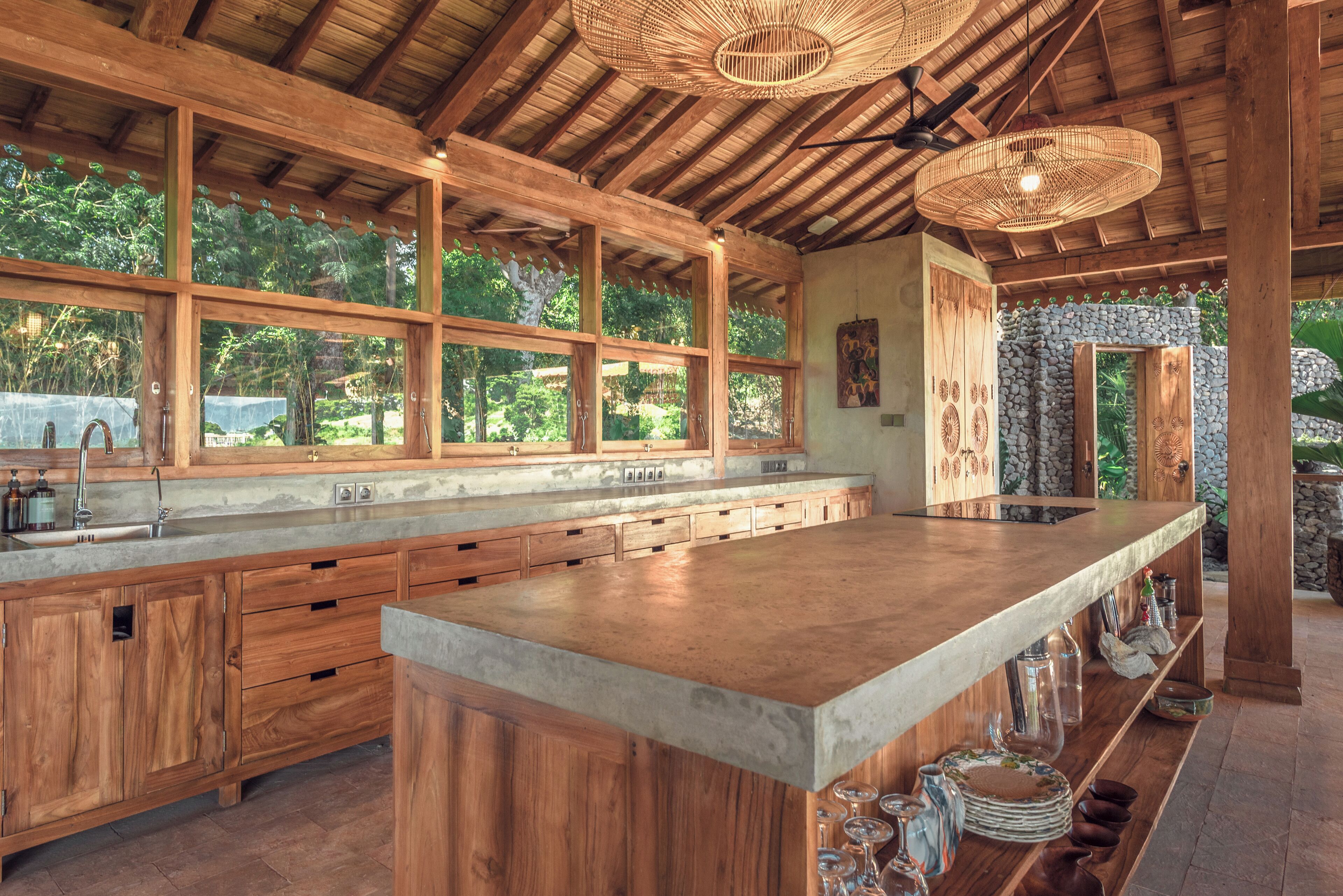 A spacious kitchen with wooden cabinets, a large island, and a stone wall.