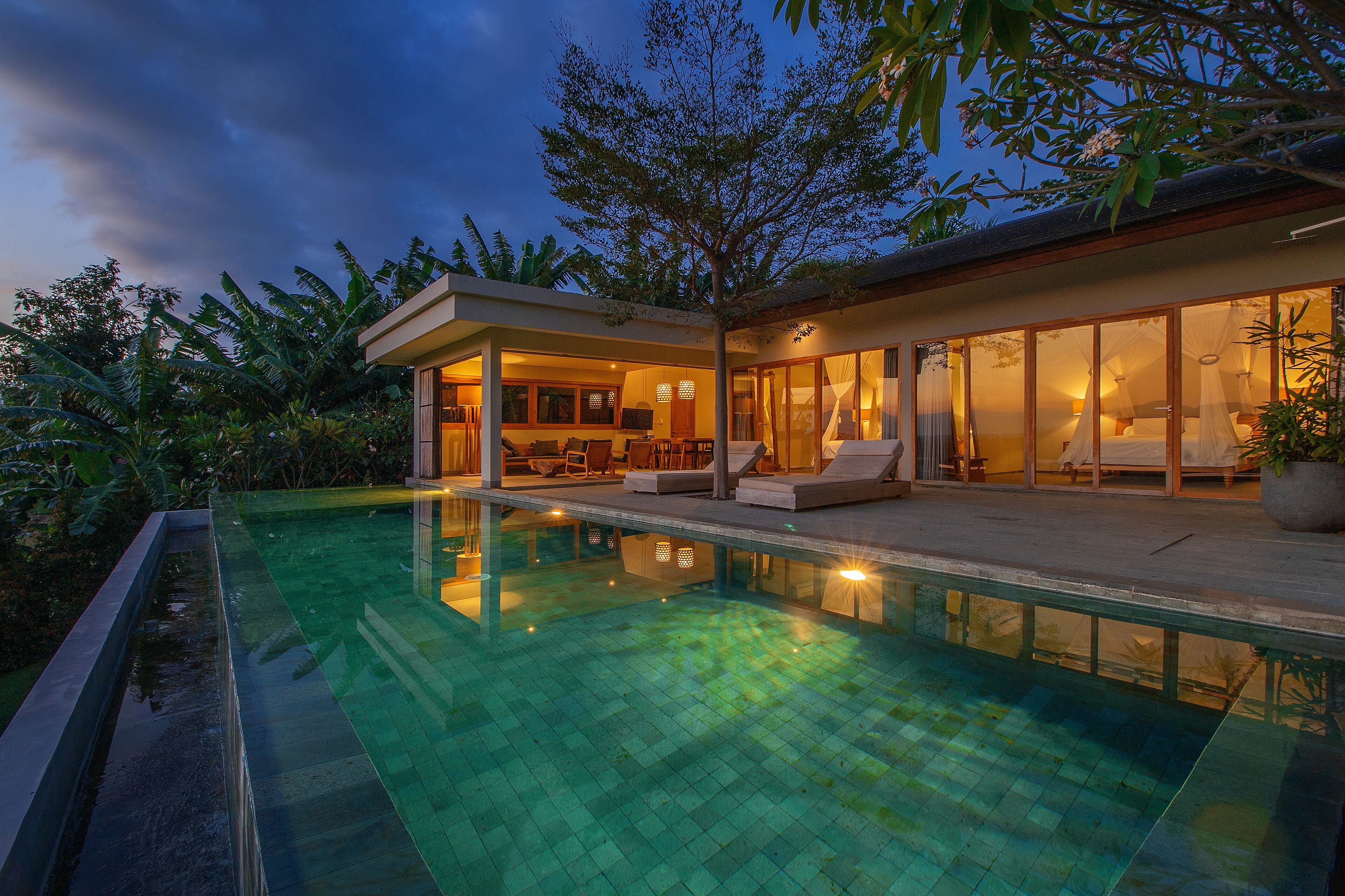 Uma casa moderna com piscina, janelas amplas e área de estar ao ar livre.