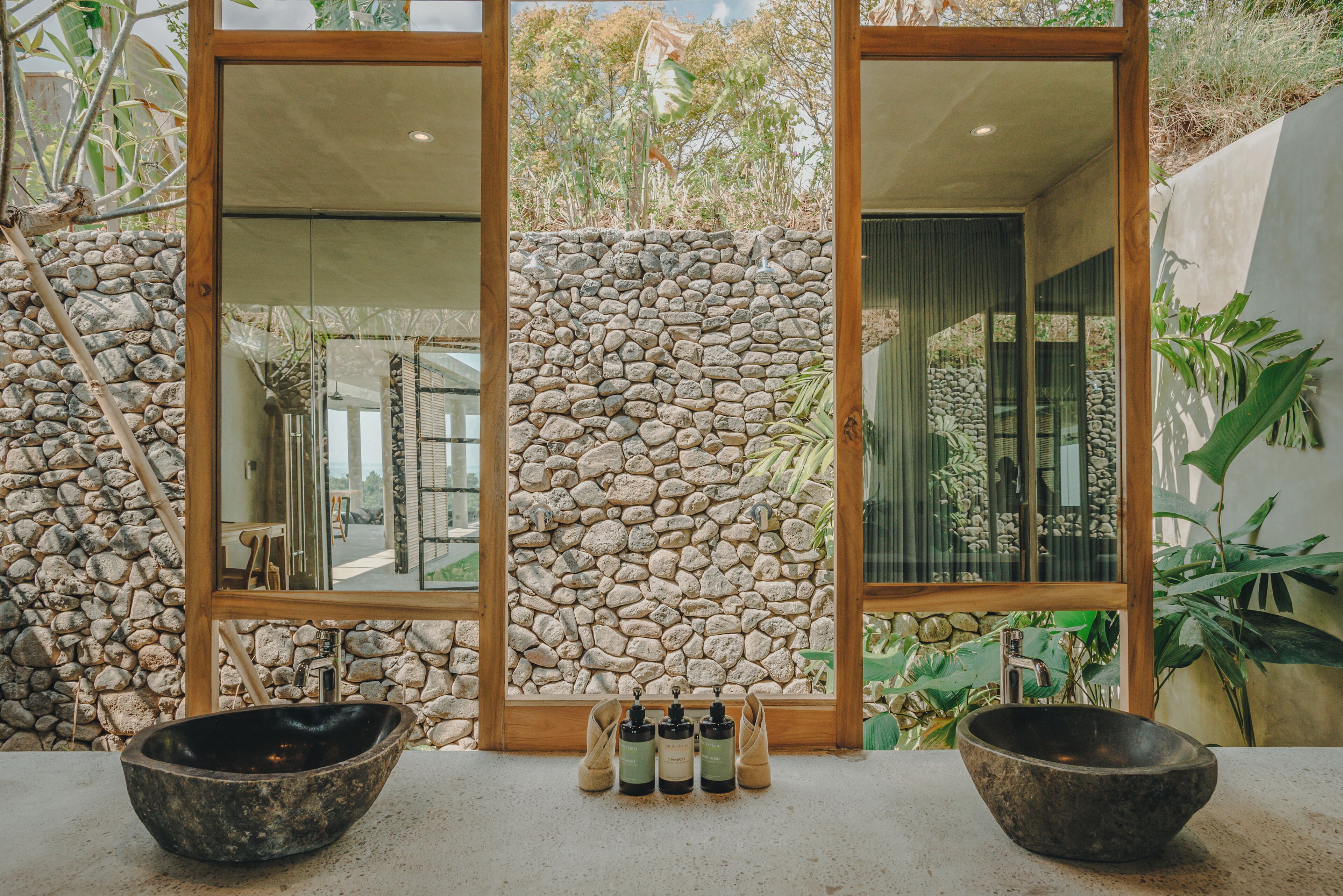 A bathroom with a stone wall, wooden doors, and a large sink.