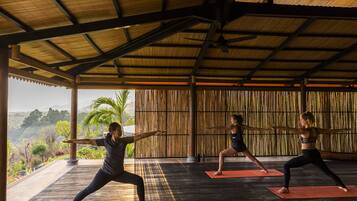 Un studio de yoga offrant une vue sur l’extérieur, avec un plafond en bois et des murs en bambou.