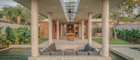 A modern outdoor pool area with a seating arrangement and a view of the interior.