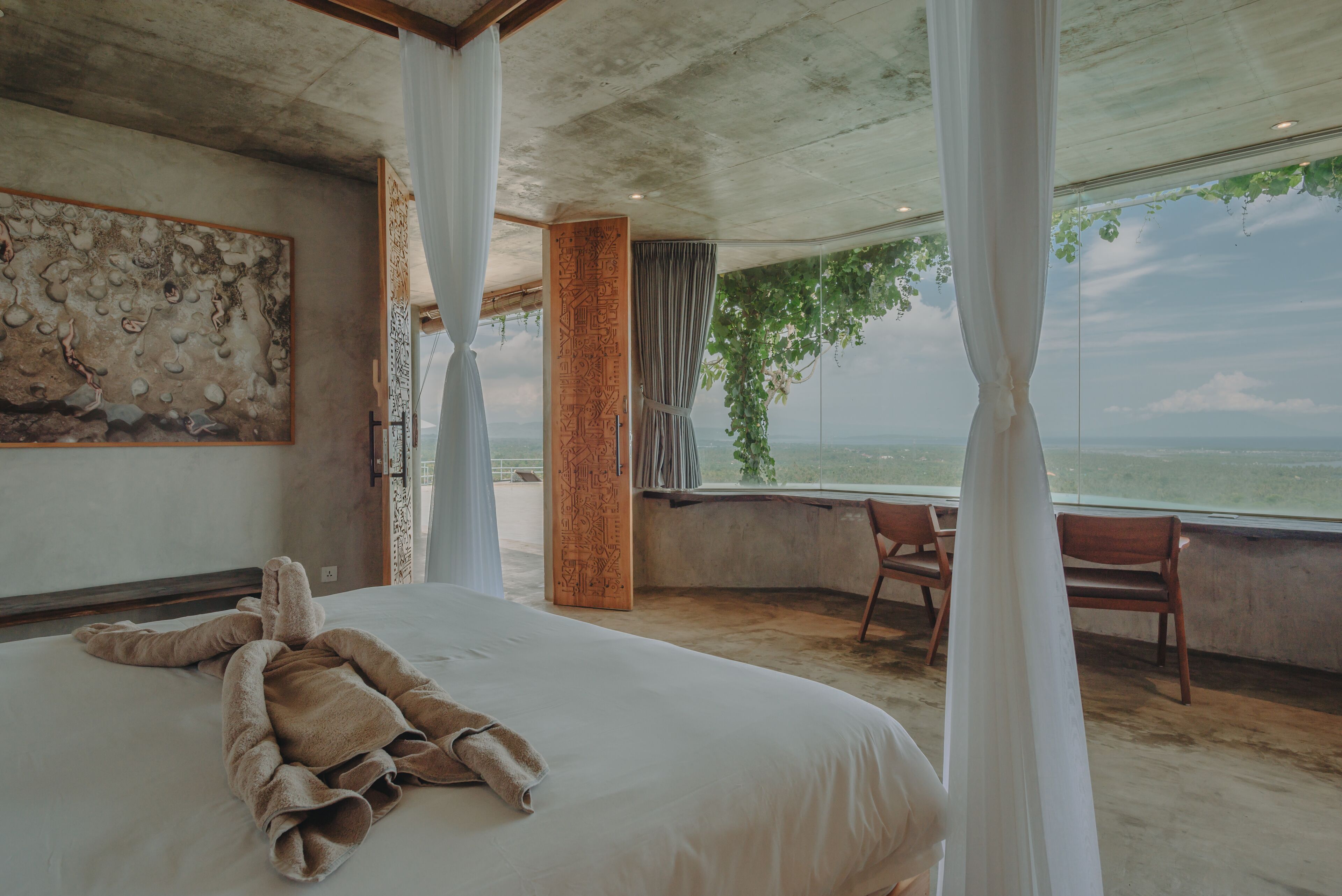 A bedroom with a large bed, a view of the sea, and a ceiling with exposed beams.