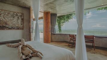 A bedroom with a large bed, a view of the sea, and a ceiling with exposed beams.